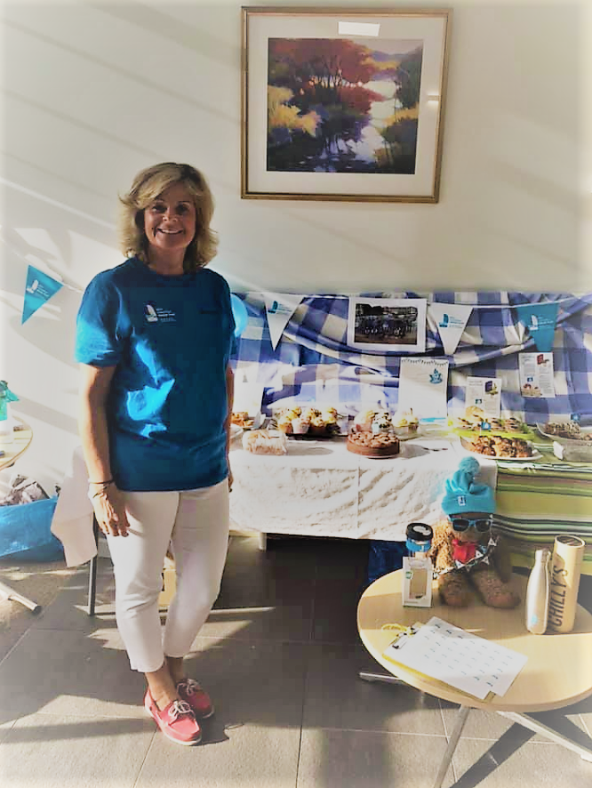 Juliet Sykes smiling beside a table with bakery and bunting, fundraising for the Trust