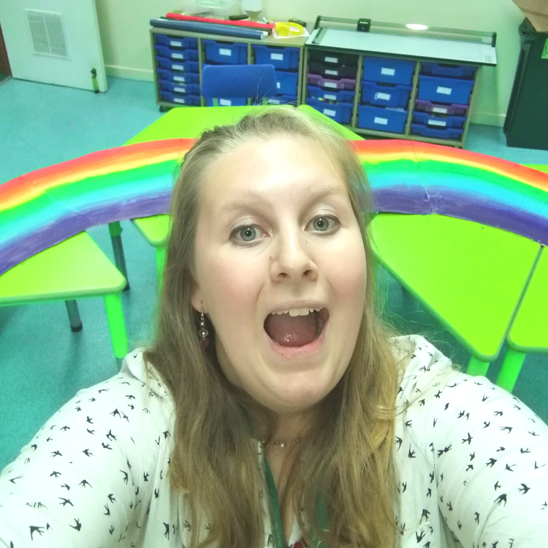 Fran taking a selfie in the school class room with the kids colour art work behind her