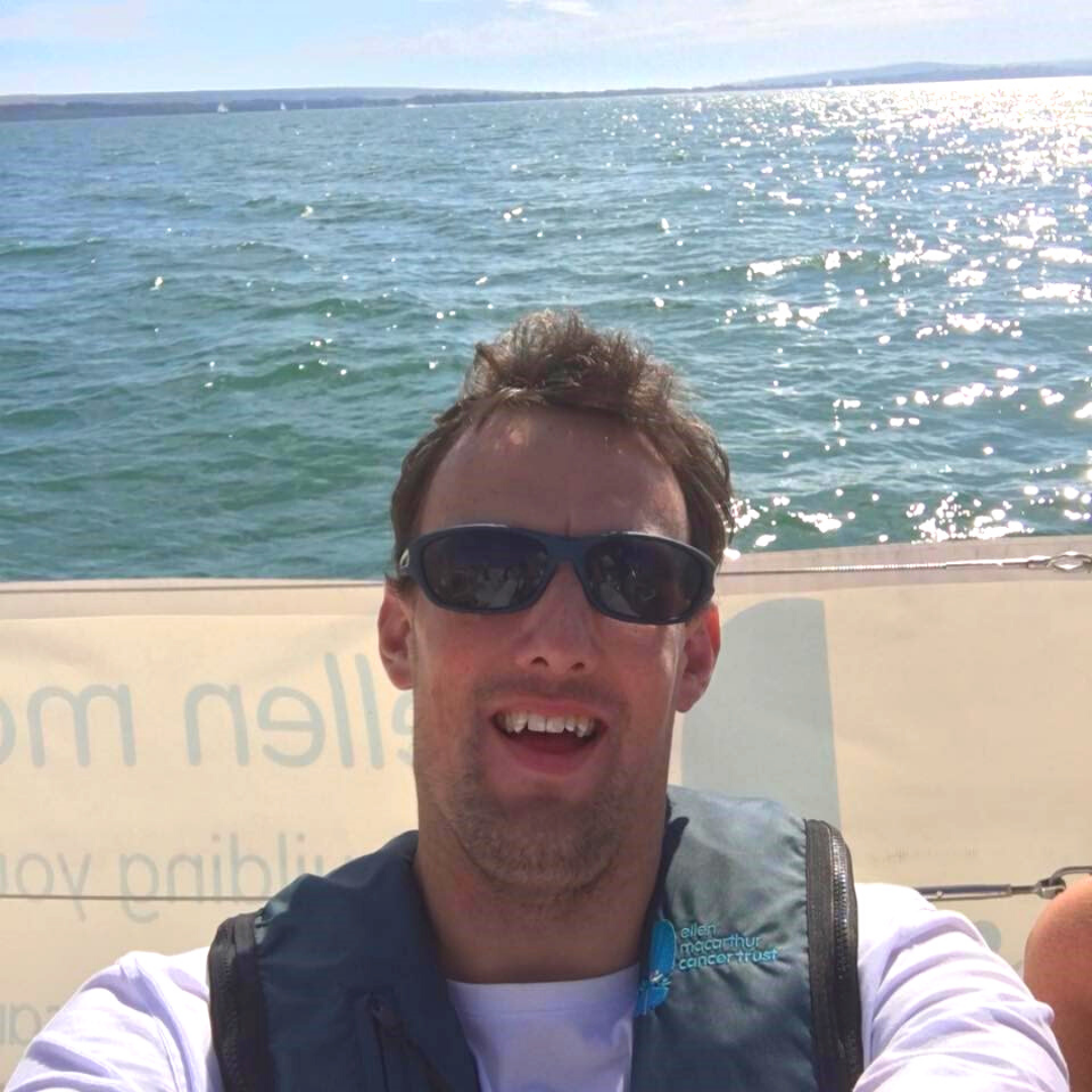 Dan Bishop taking a selfie on a Trust boat with the sea sparkling behind him